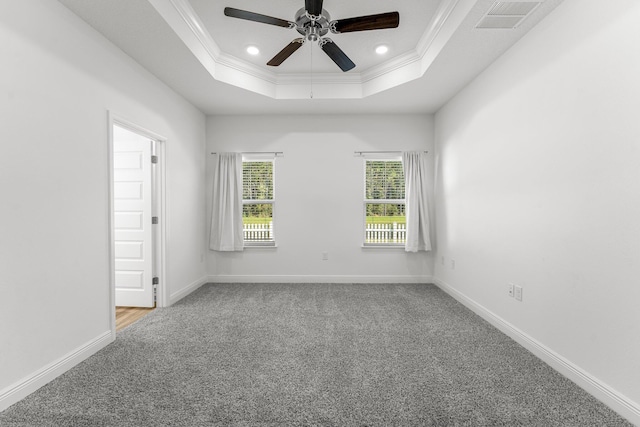 carpeted spare room featuring a tray ceiling, ceiling fan, and ornamental molding