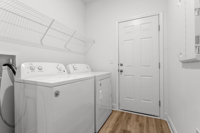 washroom with washing machine and clothes dryer and light wood-type flooring