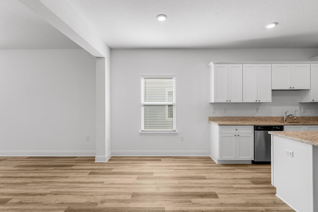 kitchen with light stone counters, light hardwood / wood-style flooring, white cabinets, and stainless steel dishwasher