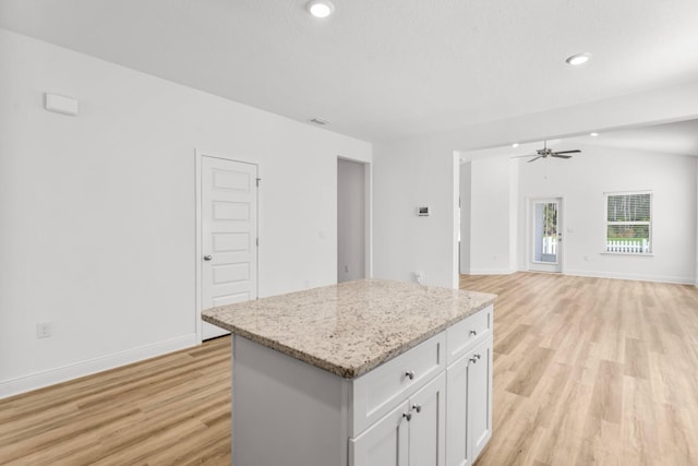 kitchen with a center island, light hardwood / wood-style flooring, white cabinetry, and light stone counters