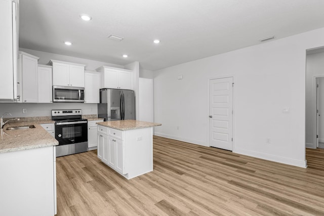 kitchen featuring sink, light hardwood / wood-style flooring, appliances with stainless steel finishes, a kitchen island, and white cabinetry