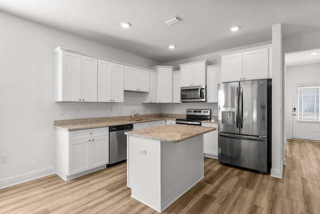 kitchen with white cabinets, appliances with stainless steel finishes, light wood-type flooring, and sink