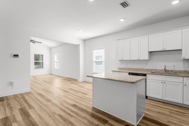 kitchen with light stone countertops, a center island, sink, light hardwood / wood-style flooring, and white cabinets