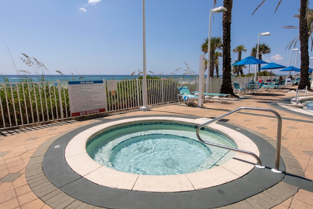 view of swimming pool with a community hot tub, a patio, and a water view