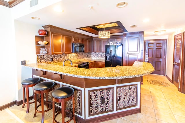 kitchen featuring light stone countertops, kitchen peninsula, pendant lighting, light tile patterned flooring, and black appliances