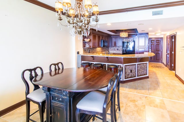 tiled dining area with a chandelier, crown molding, and sink