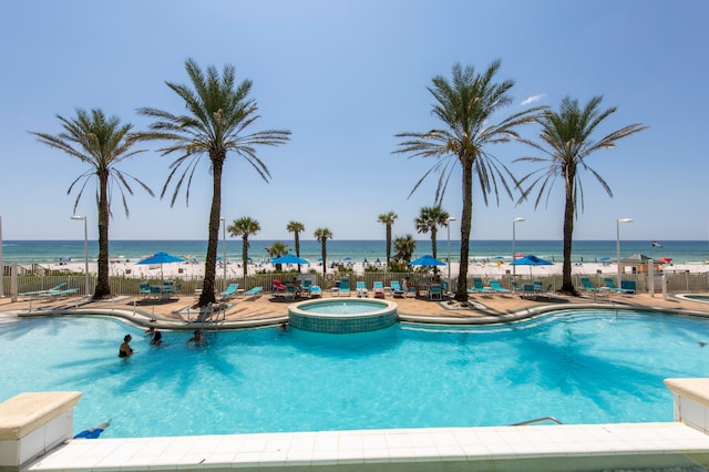 view of swimming pool with a water view, a patio, and a hot tub