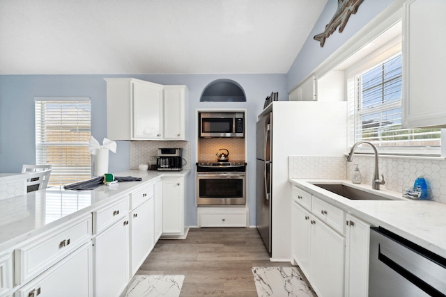 kitchen with light stone counters, white cabinetry, and appliances with stainless steel finishes