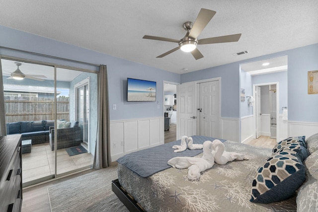 bedroom featuring ceiling fan, light hardwood / wood-style flooring, ensuite bathroom, a textured ceiling, and access to outside