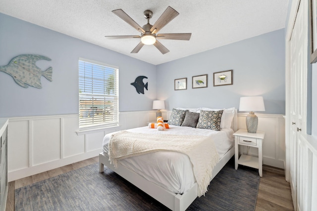 bedroom with a textured ceiling, a closet, ceiling fan, and dark wood-type flooring