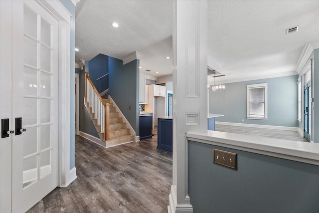 kitchen with an inviting chandelier, dark hardwood / wood-style floors, blue cabinets, crown molding, and a textured ceiling