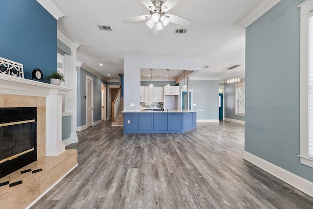 kitchen with a tile fireplace, crown molding, wood-type flooring, and decorative light fixtures