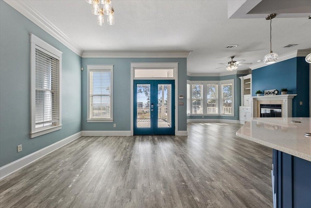 entryway with french doors, dark hardwood / wood-style flooring, a textured ceiling, ceiling fan with notable chandelier, and ornamental molding