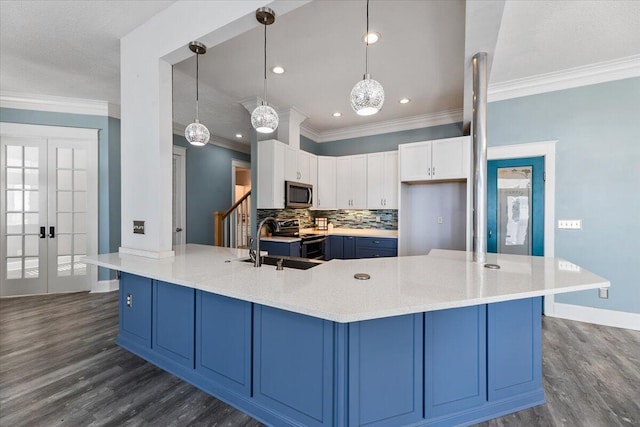 kitchen with appliances with stainless steel finishes, sink, pendant lighting, white cabinets, and dark hardwood / wood-style floors