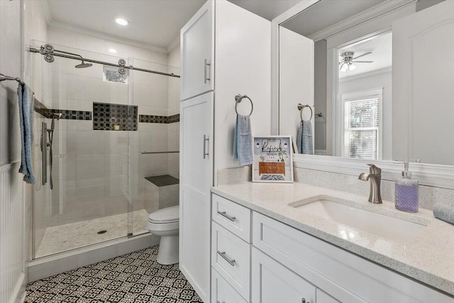 bathroom with vanity, a shower with door, crown molding, ceiling fan, and toilet