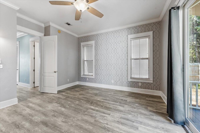 spare room featuring a wealth of natural light, crown molding, ceiling fan, and light wood-type flooring