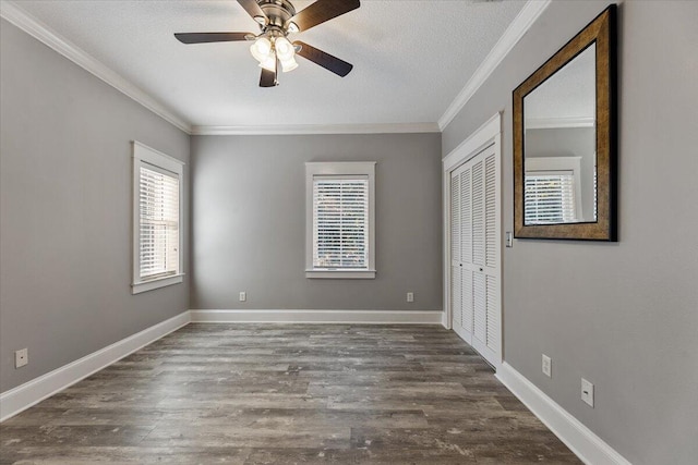 unfurnished bedroom with dark hardwood / wood-style flooring, ornamental molding, a textured ceiling, ceiling fan, and a closet