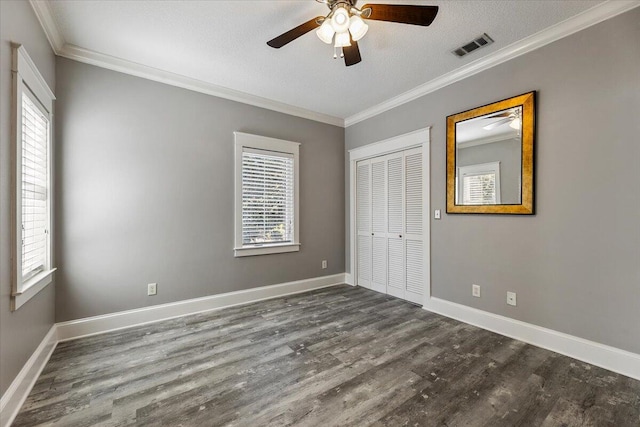 unfurnished bedroom featuring ceiling fan, dark hardwood / wood-style floors, ornamental molding, a textured ceiling, and a closet