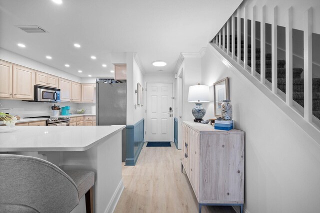 kitchen featuring a breakfast bar, light brown cabinets, appliances with stainless steel finishes, light hardwood / wood-style floors, and kitchen peninsula