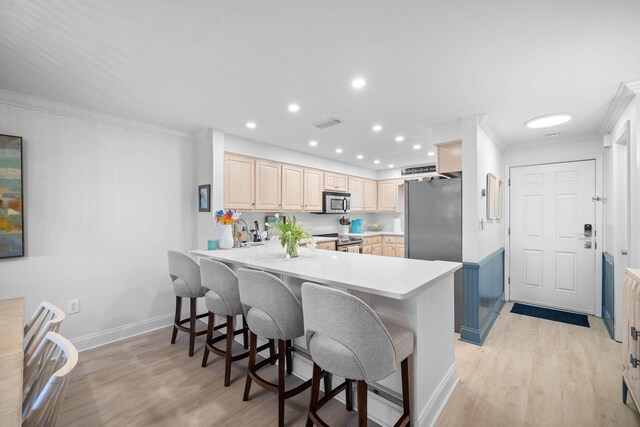 kitchen with light wood-type flooring, kitchen peninsula, stainless steel appliances, and ornamental molding