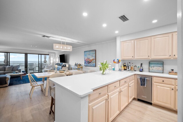 kitchen featuring kitchen peninsula, dishwasher, light hardwood / wood-style floors, and a breakfast bar