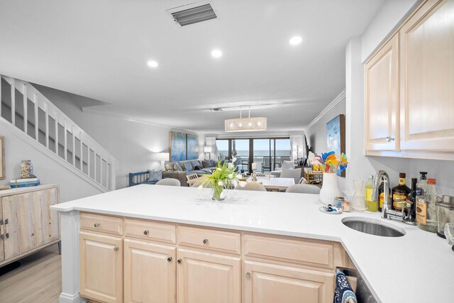 kitchen with sink, light brown cabinets, light hardwood / wood-style flooring, kitchen peninsula, and ornamental molding