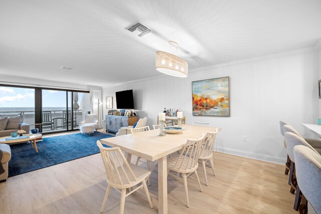 dining area featuring light wood-type flooring and crown molding