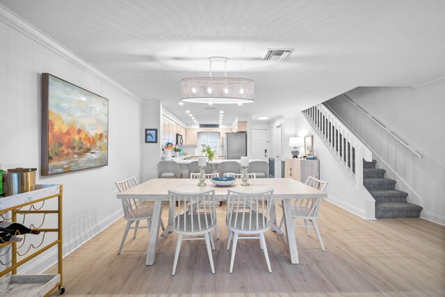 dining space featuring light wood-type flooring and crown molding