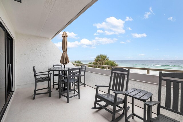 balcony with a water view and a view of the beach