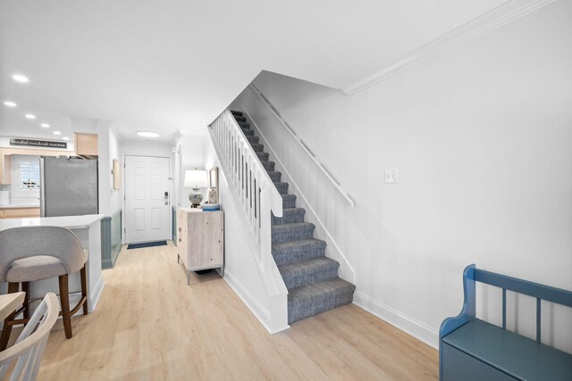 stairway with hardwood / wood-style flooring and crown molding