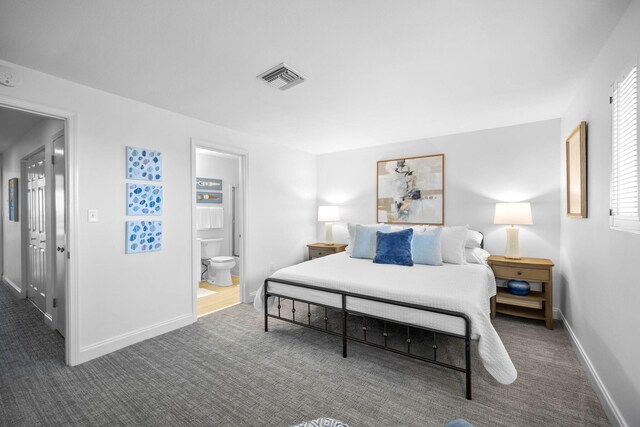 bedroom with ensuite bath and dark carpet