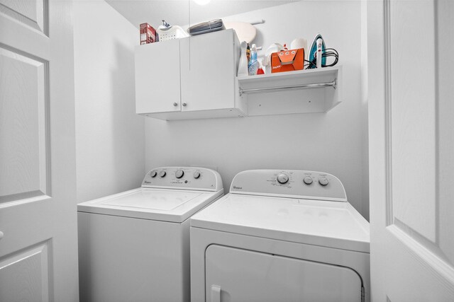 clothes washing area featuring cabinets and washing machine and dryer