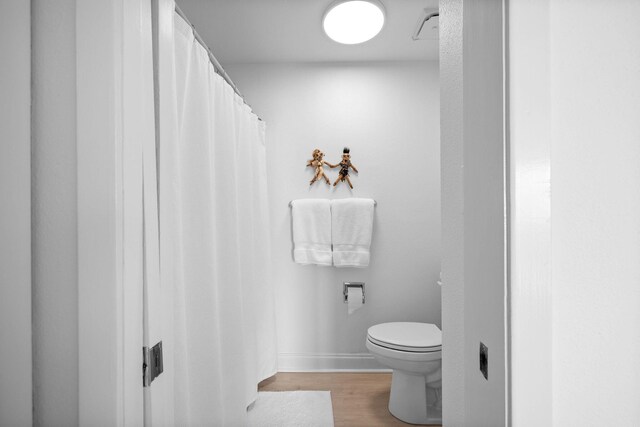 bathroom featuring wood-type flooring and toilet