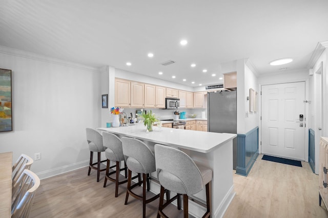 kitchen featuring kitchen peninsula, crown molding, light wood-type flooring, and appliances with stainless steel finishes