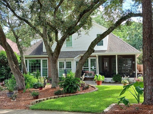 view of front of property featuring a sunroom and a front lawn