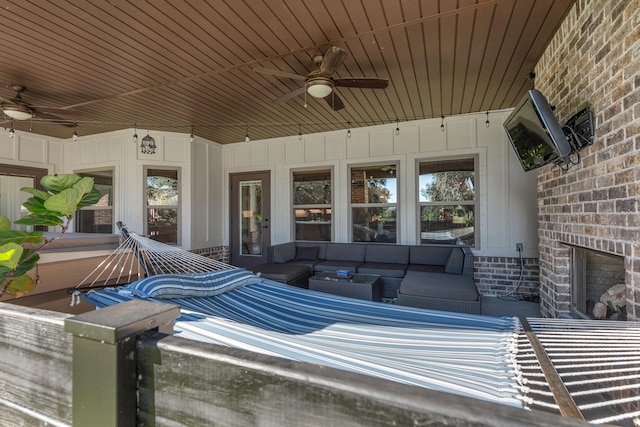 view of patio / terrace featuring ceiling fan and an outdoor living space with a fireplace