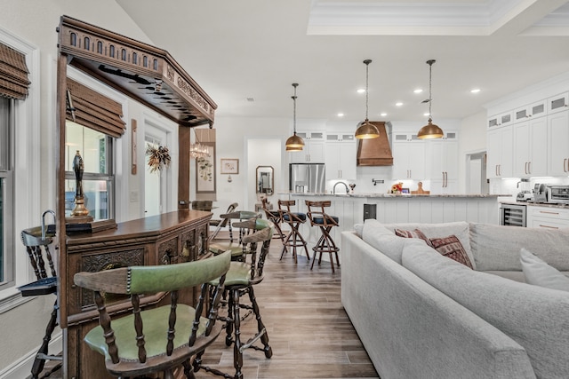 living room featuring sink, crown molding, dark wood-type flooring, and beverage cooler