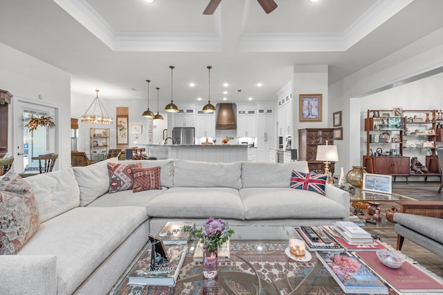 living room featuring ornamental molding, ceiling fan with notable chandelier, and wood-type flooring