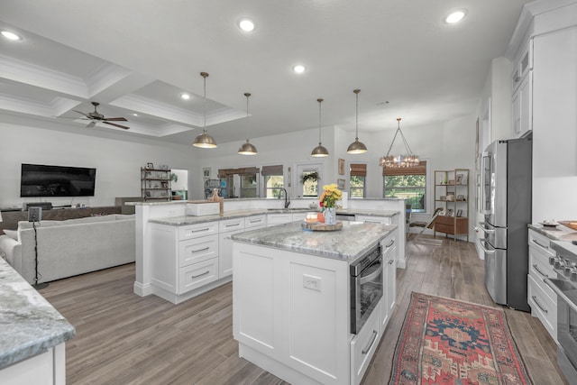 kitchen featuring beam ceiling, decorative light fixtures, a center island, and white cabinets