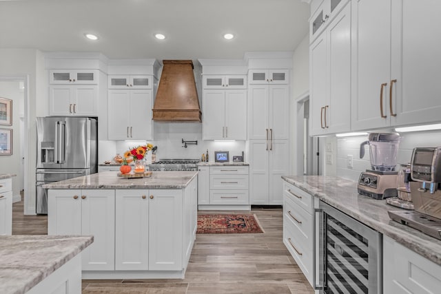 kitchen with high quality fridge, white cabinets, beverage cooler, custom exhaust hood, and light stone counters