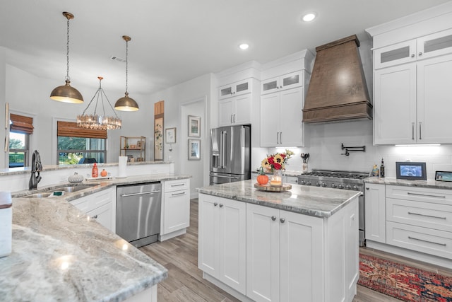 kitchen with high end appliances, hanging light fixtures, custom exhaust hood, and white cabinets