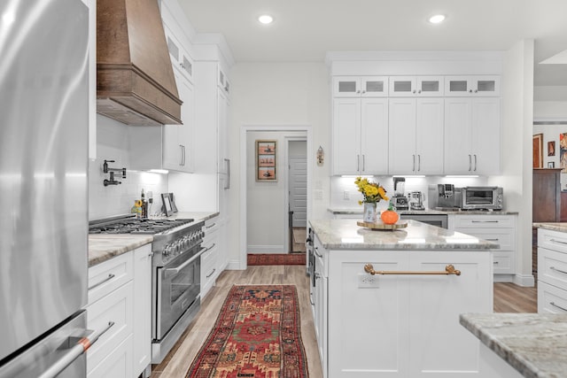 kitchen with stainless steel appliances, white cabinets, and light stone counters