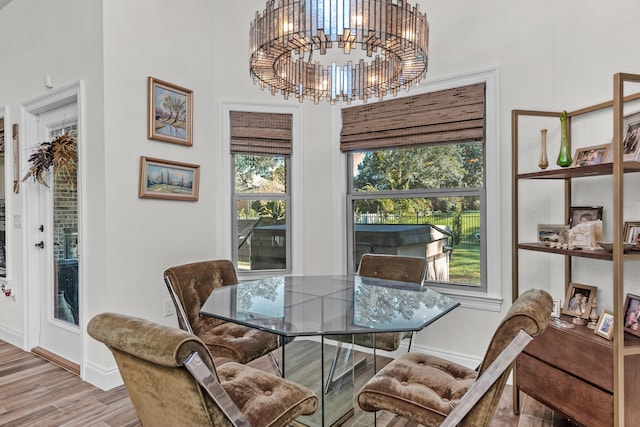 dining room with a notable chandelier, a towering ceiling, light hardwood / wood-style floors, and a healthy amount of sunlight