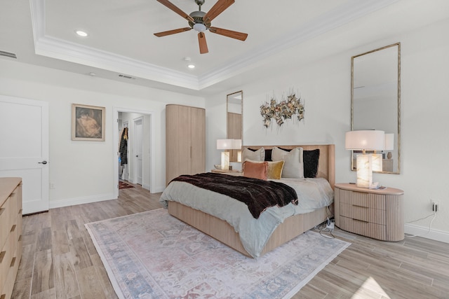 bedroom featuring crown molding, light hardwood / wood-style floors, a raised ceiling, and ceiling fan