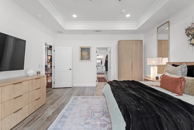 bedroom featuring crown molding, light hardwood / wood-style floors, and a tray ceiling