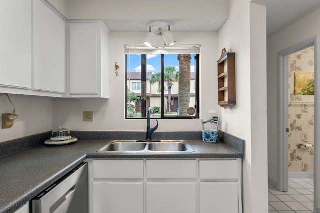 kitchen with white cabinets, sink, stainless steel dishwasher, light tile patterned flooring, and a chandelier