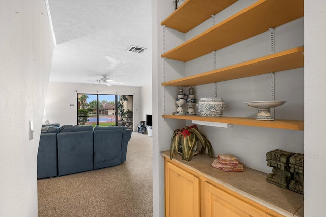 carpeted living room with a textured ceiling and ceiling fan