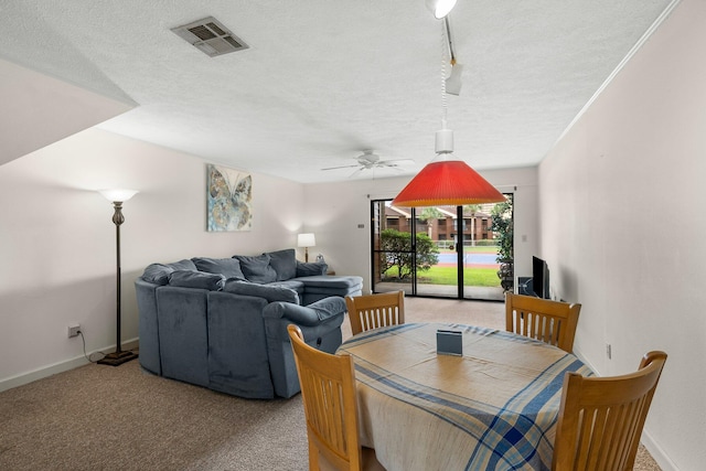 carpeted dining space featuring ceiling fan, track lighting, and a textured ceiling