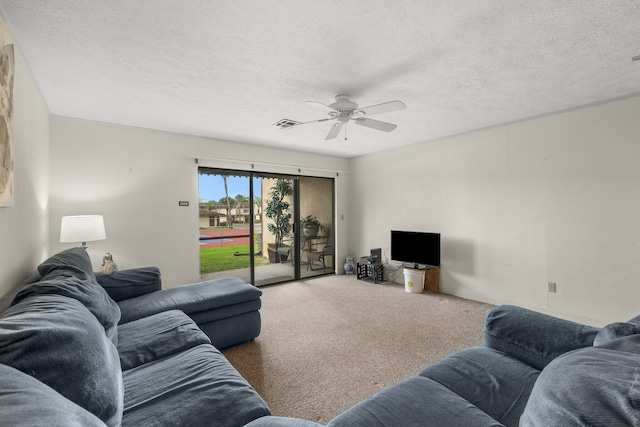 carpeted living room featuring ceiling fan and a textured ceiling