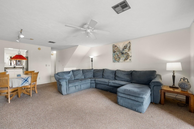 carpeted living room featuring ceiling fan and a textured ceiling